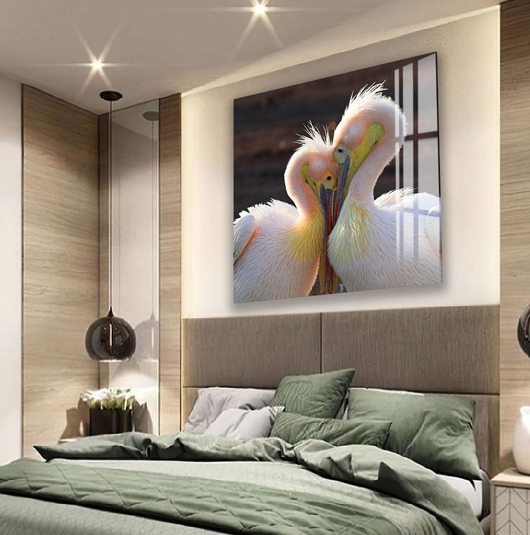 a large, colorful painting of two pelicans on a wall above a bed with a green comforter.