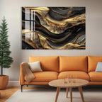 a modern living room with a large abstract painting hanging on the wall above a cozy orange sofa. The painting has a striking black and gold color scheme, with swirling patterns and textures that create a sense of depth and movement. In front of the sofa, there is a wooden coffee table with a glass top, and a potted plant is placed on the floor next to the sofa.