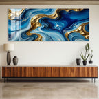 a large abstract painting with swirling blue and gold colors, hanging on a wall above a wooden cabinet.