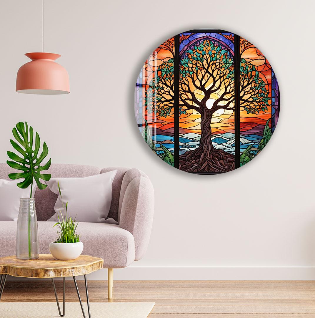 a living room with a large circular wall art depicting a colorful stained glass tree with a sunset in the background. The room has a pink pendant light, a gray sofa, and a wooden coffee table.