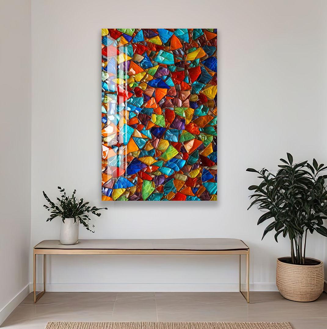 a vibrant, colorful abstract painting hanging on a white wall above a wooden bench and a potted plant.
