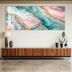 a large abstract painting with a vibrant color palette of blue, pink, and green, with gold accents. The painting is displayed on a wall above a wooden cabinet or entertainment center, which has a lamp and two potted plants on it.