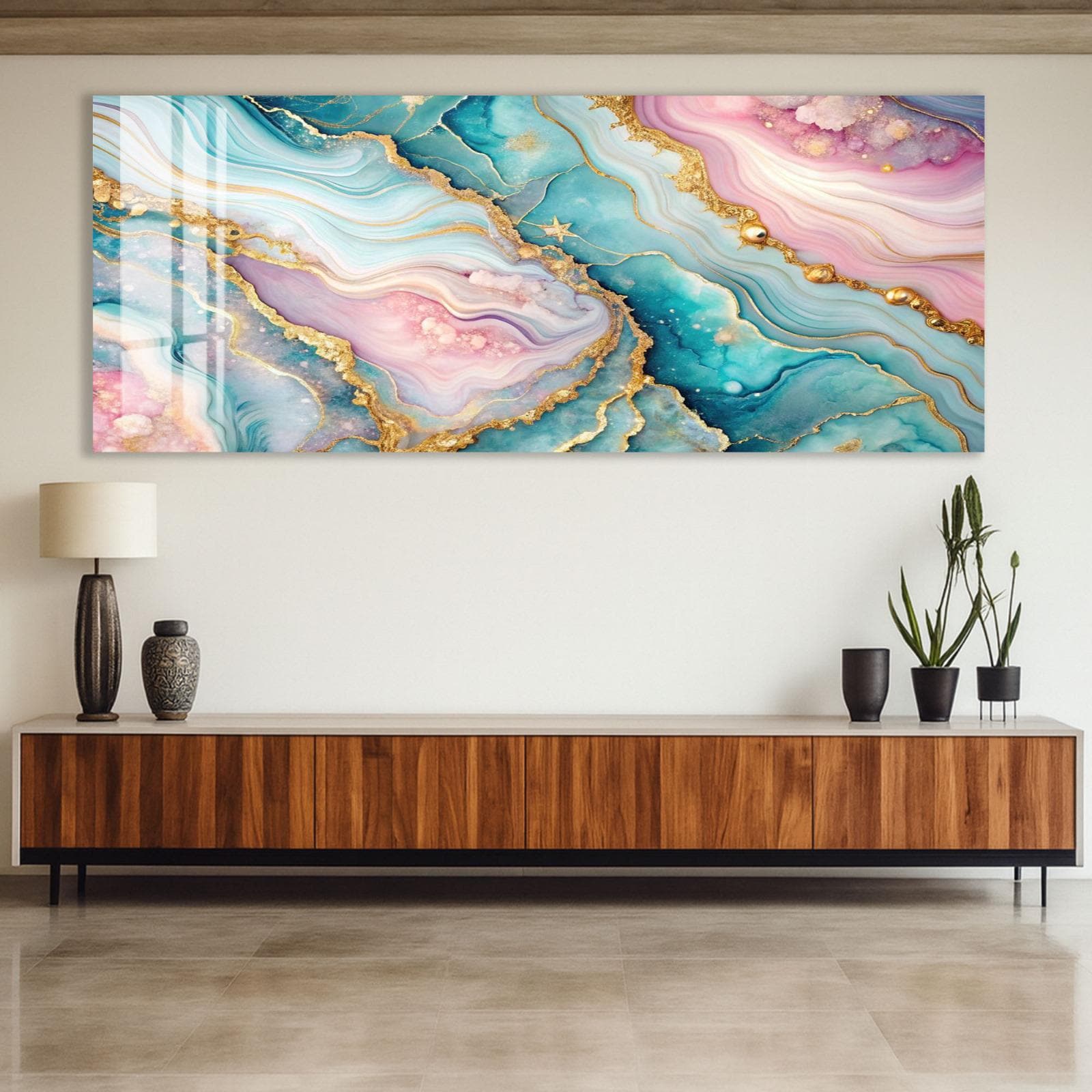 a large abstract painting with a vibrant color palette of blue, pink, and green, with gold accents. The painting is displayed on a wall above a wooden cabinet or entertainment center, which has a lamp and two potted plants on it.
