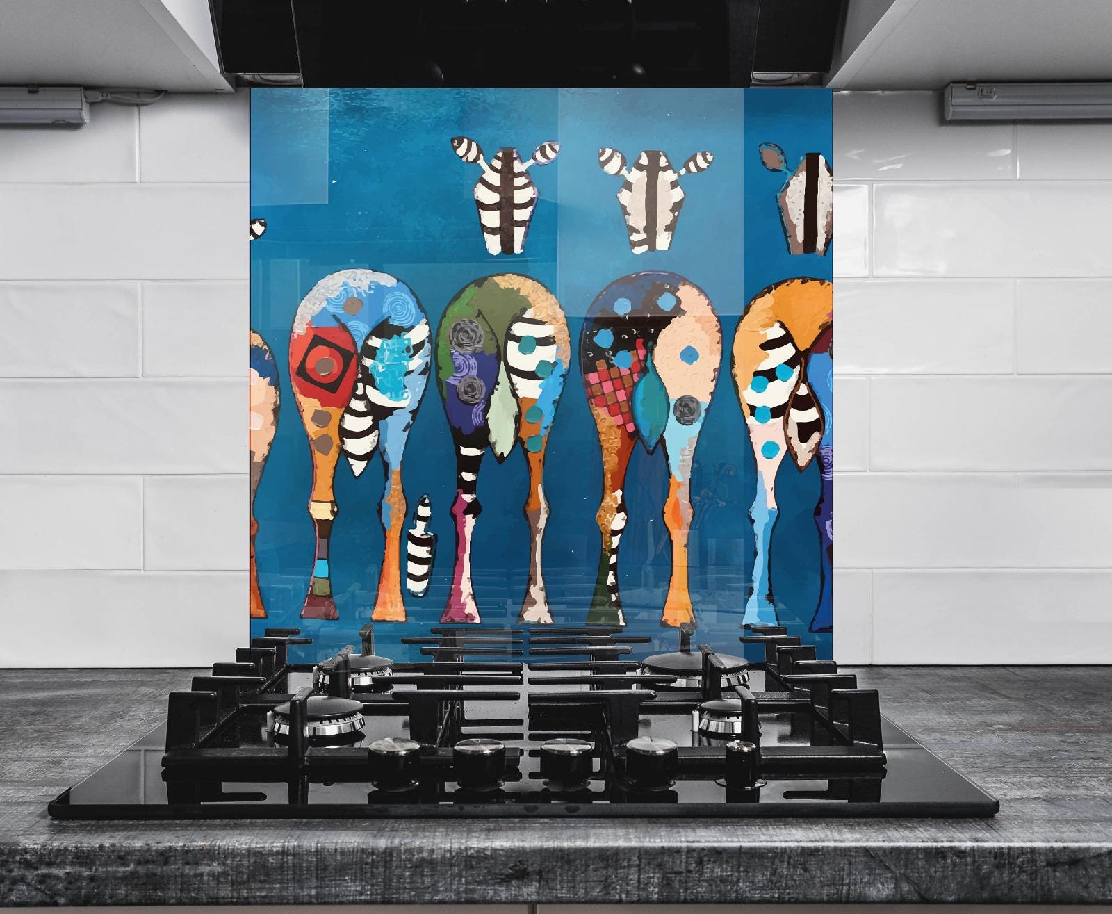 a modern kitchen with a striking blue and white color scheme. The focal point is a black gas stove with a unique design, positioned in front of a large, colorful mural depicting a group of stylized animal heads. The mural is a vibrant mix of various colors and patterns, creating a lively and dynamic visual contrast against the white tiled wall.