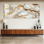 a large marble-like wall art piece with a gold-colored marble texture, hanging above a wooden cabinet or console table with two black vases on top.