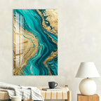 a large abstract painting with a swirling pattern of turquoise and gold colors, hanging on a wall above a wooden table with a lamp and a book.