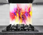 a vibrant abstract painting with a colorful, swirling design of pink, orange, yellow, and purple hues. The painting is displayed on a wall behind a gas stove, creating a visually striking contrast between the modern kitchen appliances and the artistic artwork.