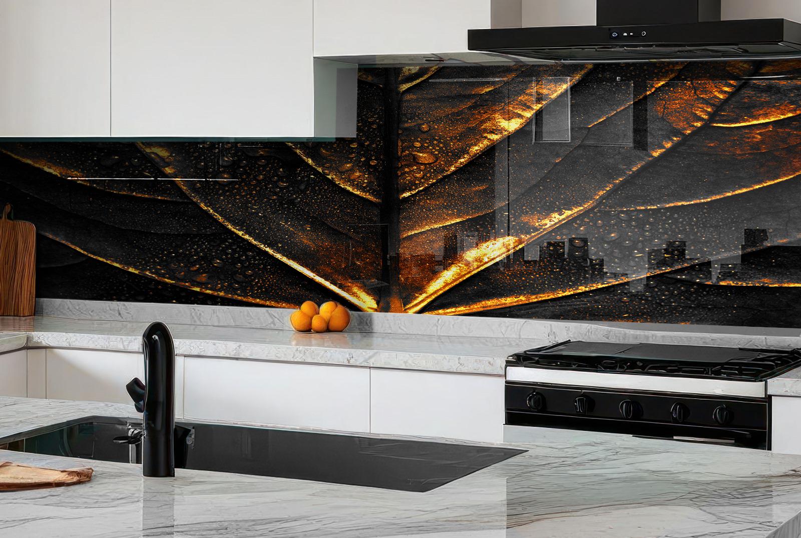 a modern kitchen with a black and white color scheme. The kitchen has a sleek black stove and a marble countertop. On the countertop, there are a few oranges and a cutting board. The wall behind the countertop has a striking black and gold design, creating a visually appealing contrast with the white cabinets and marble countertop.