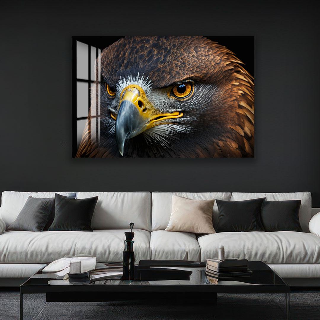 a large, close-up of a bird of prey, such as an eagle or hawk, with its sharp beak and piercing eyes. The bird is positioned in the center of the frame, drawing the viewer's attention to its striking features. The background is dark, which contrasts with the bird's colors and makes it stand out even more. The image is displayed on a wall above a white couch, creating a striking visual focal point in the room.