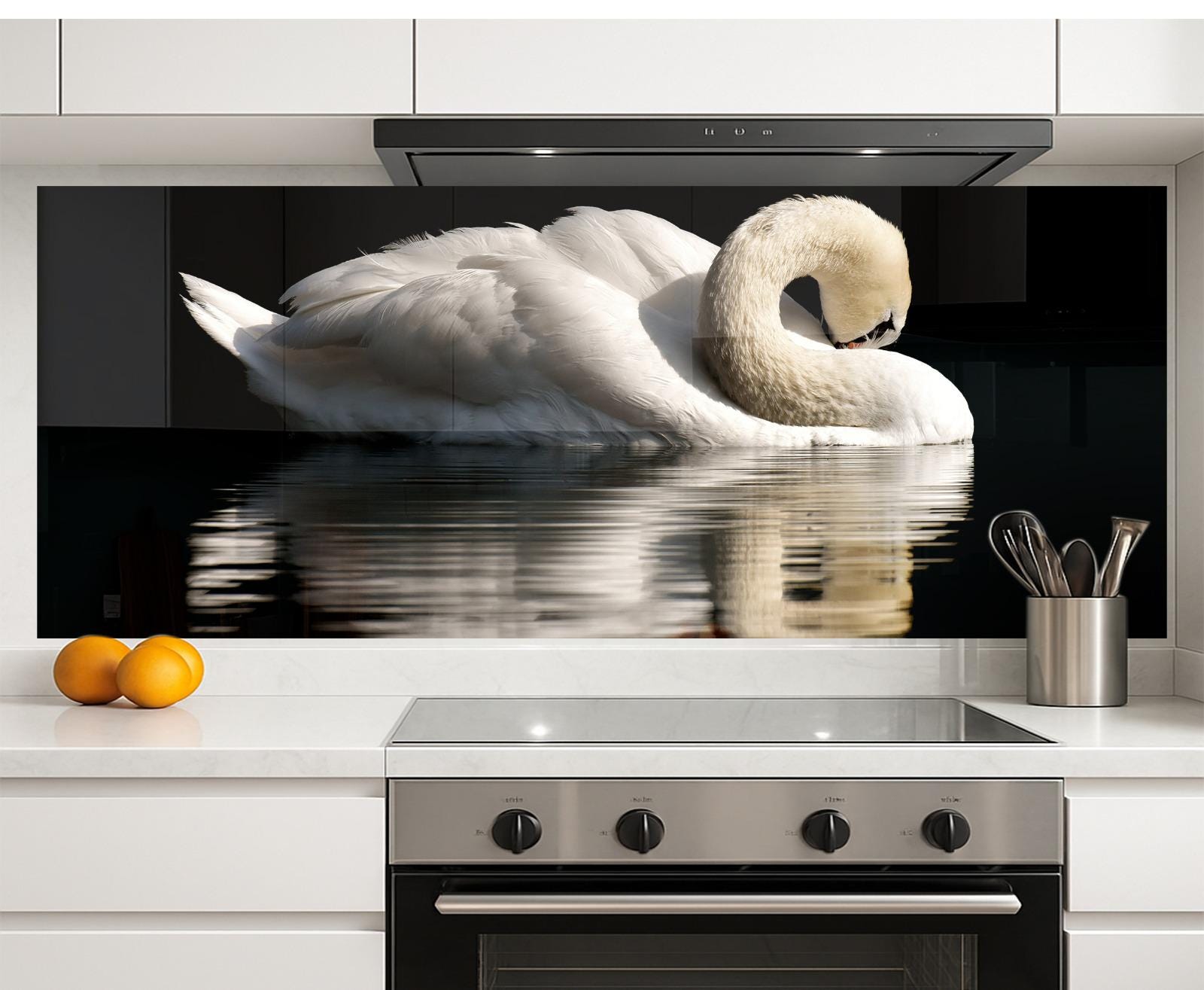 A large, white swan swimming in a body of water is displayed on a kitchen backsplash, with a stainless steel oven and a bowl of oranges on the countertop below.