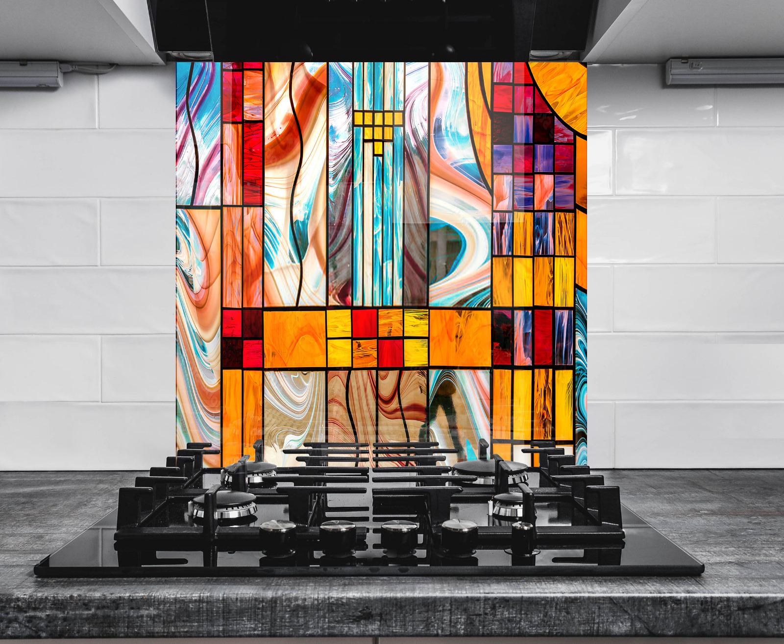 a modern kitchen with a large, colorful stained glass window as the focal point. The window is composed of various geometric shapes and patterns in a range of vibrant colors, including red, orange, yellow, green, blue, and purple. The window is set against a white wall, and the kitchen has a black stovetop and countertop.