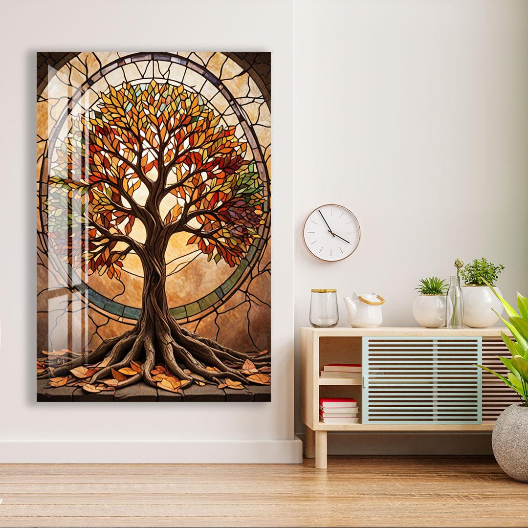 a large stained glass window depicting a tree with vibrant autumn leaves, set against a white wall. The window is framed by a wooden border, and a clock is mounted on the wall above it. To the right of the window, there is a wooden cabinet with a glass door, and a small plant is placed on top of the cabinet.