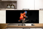 a vibrant orange goldfish swimming in a kitchen sink, with a black background and white cabinets in the background.