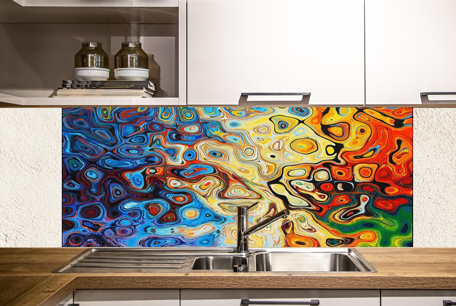 a kitchen with a colorful, abstract backsplash behind the sink. The backsplash has a vibrant mix of blue, orange, yellow, and green swirls and patterns. The sink is positioned under the backsplash, and there are some bottles visible on a shelf above it.