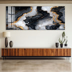 a modern interior design with a large abstract painting hanging on the wall above a wooden cabinet. The painting has a striking black and white marble-like pattern with gold accents, creating a visually striking contrast. The cabinet below the painting has a sleek, contemporary design with a dark finish, complementing the overall aesthetic of the room.