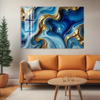 a modern living room with a large abstract painting hanging on the wall above a cozy orange sofa. The painting has swirling patterns of blue and gold colors, creating a visually striking and dynamic design. In front of the sofa, there is a wooden coffee table with a glass top, and a potted plant is placed on the floor next to the sofa.