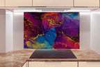a kitchen counter with a large, colorful abstract painting hanging above it. The painting has a vibrant mix of purple, blue, and yellow colors, creating a lively and dynamic visual effect. The kitchen counter appears to be made of marble, adding a touch of elegance and sophistication to the space.