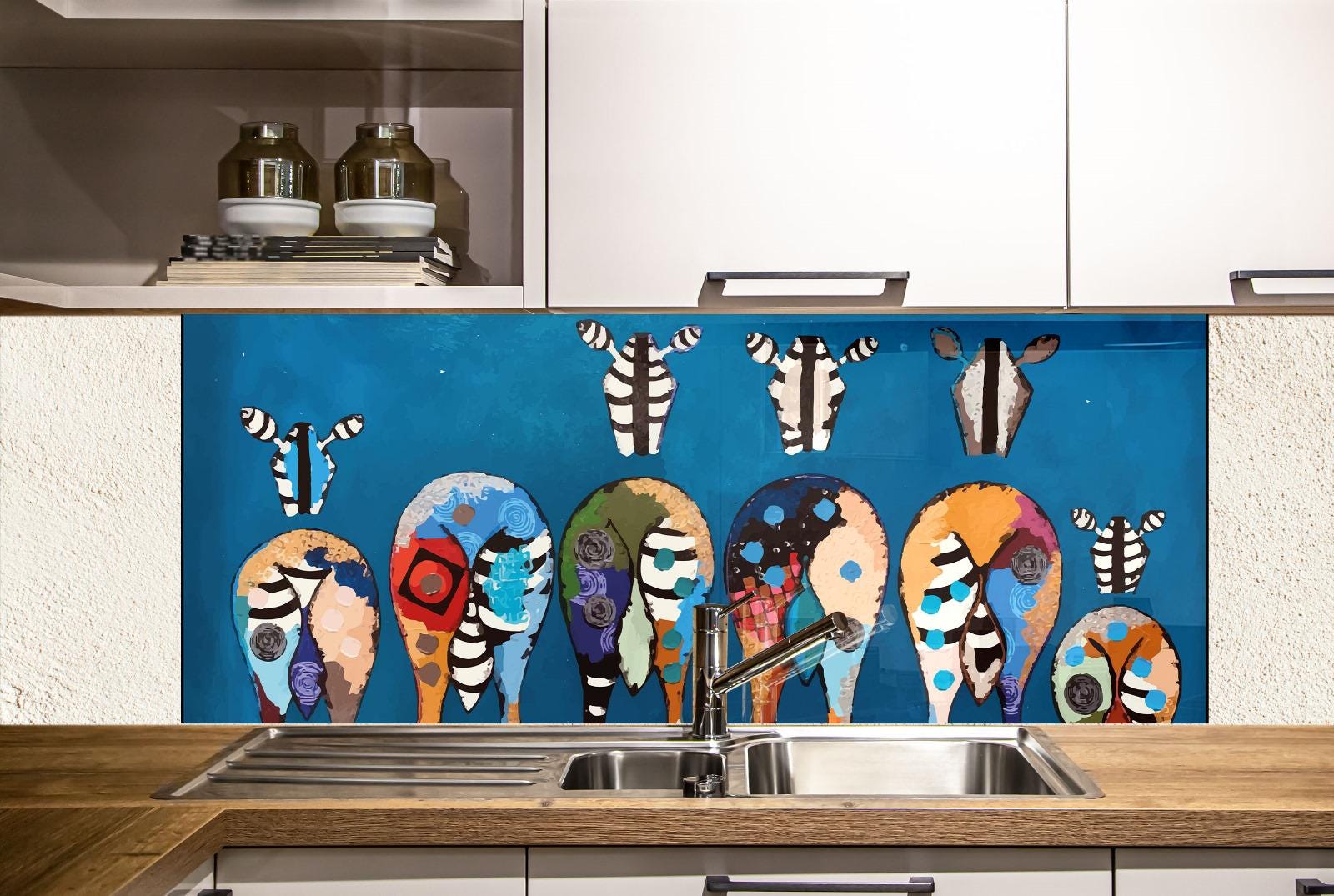 a kitchen with a blue backsplash that displays a vibrant, colorful illustration of various animal shapes, including zebras, elephants, and giraffes. The backsplash is mounted above a stainless steel sink, and there are white cabinets visible in the background.