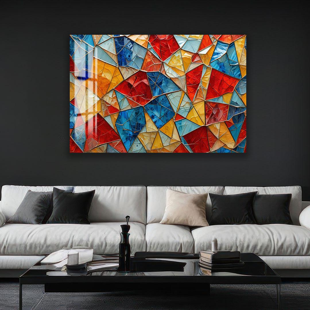 a modern living room with a large, colorful abstract painting hanging on the wall above a white sofa. The painting is composed of various geometric shapes in vibrant colors such as red, blue, yellow, and orange. The room also includes a black coffee table and a few books, creating a cozy and stylish atmosphere.