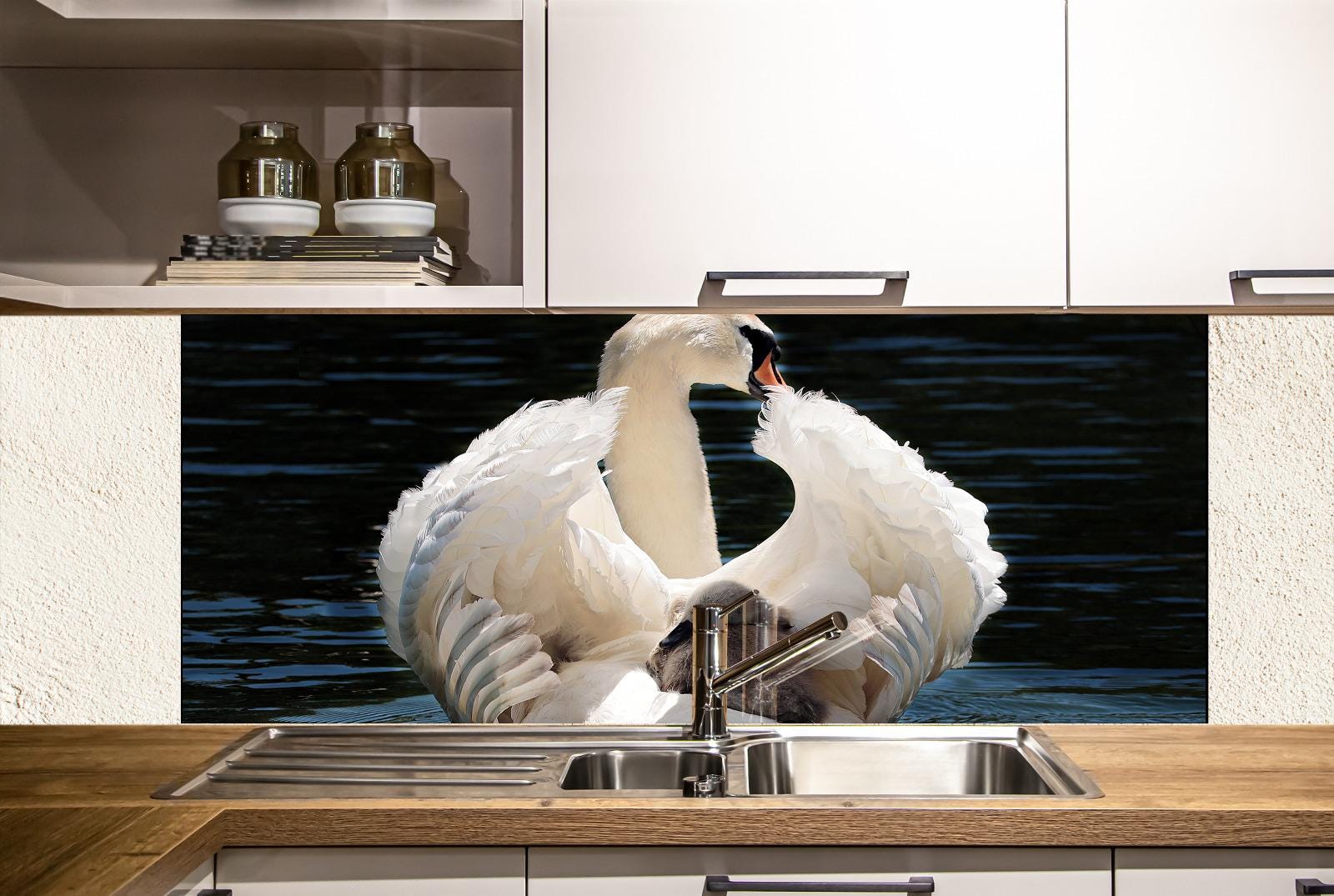 A large white swan with its wings spread is standing in a kitchen sink, with a dark background and a shelf above the sink.