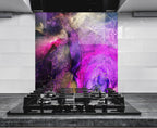 a modern kitchen with a striking abstract mural on the wall behind a gas stove. The mural displays a vibrant mix of purple, pink, and gold colors, creating a visually captivating backdrop for the kitchen&#39;s design.
