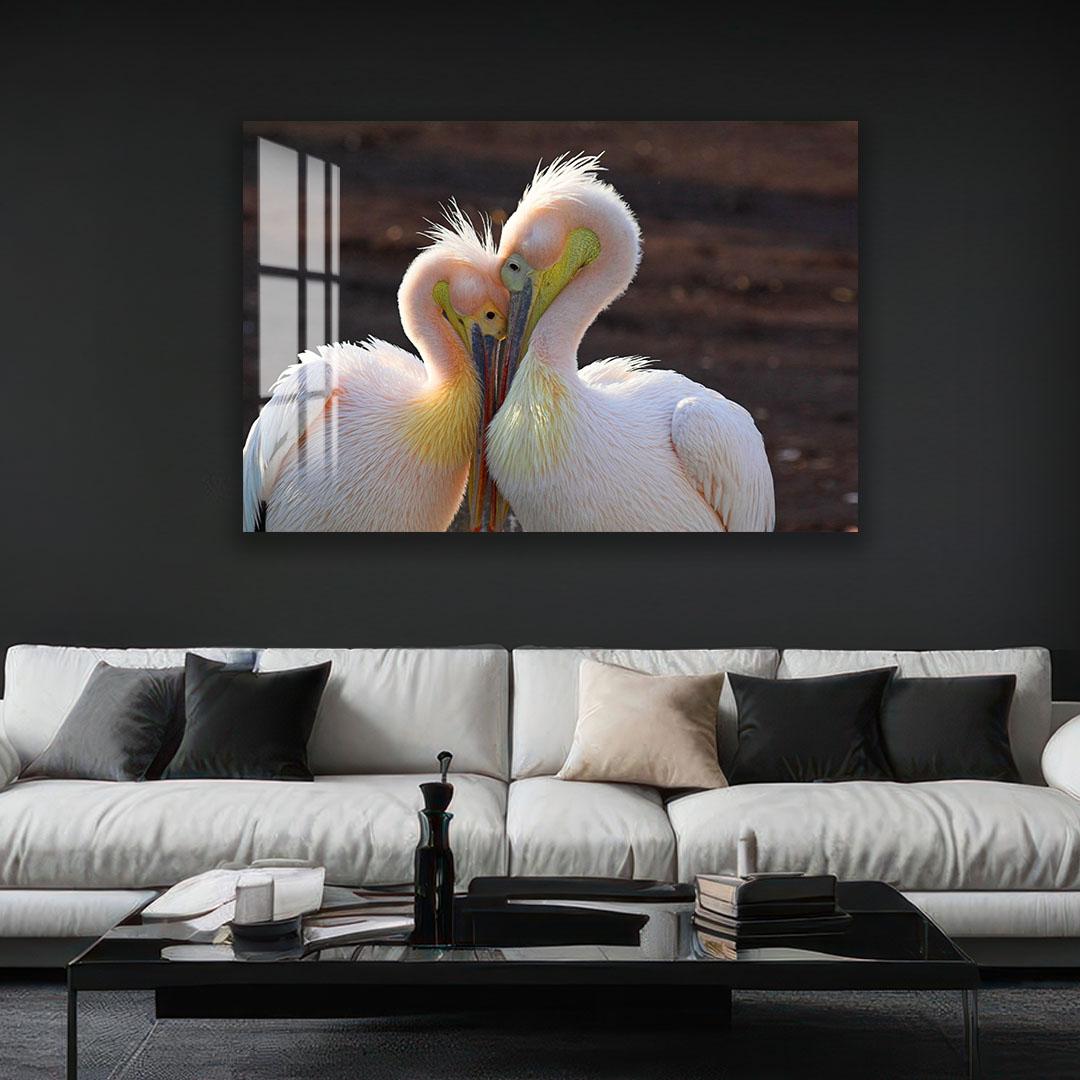 A large framed photograph of two pelicans standing close together, with their beaks touching, is displayed on the wall above a white couch in a living room setting.
