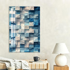 a modern art piece with a geometric pattern of blue and white squares on a white wall. Below the artwork, there is a wooden coffee table with a black mug and a book.