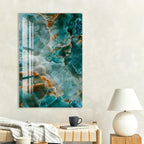 a large abstract painting with a vibrant mix of blue, orange, and green colors, hanging on a wall above a wooden table with a lamp and a book.