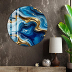 a large circular wall art piece with a swirling pattern of blue and gold colors, hanging on a wall next to a wooden shelf with a lamp and a plant.