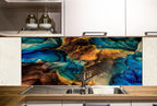 a kitchen with a colorful backsplash that has a swirling, abstract design in shades of blue, green, and brown. The backsplash is mounted above a stainless steel sink, which is situated on a wooden countertop. There are also some bottles and a book visible in the background.