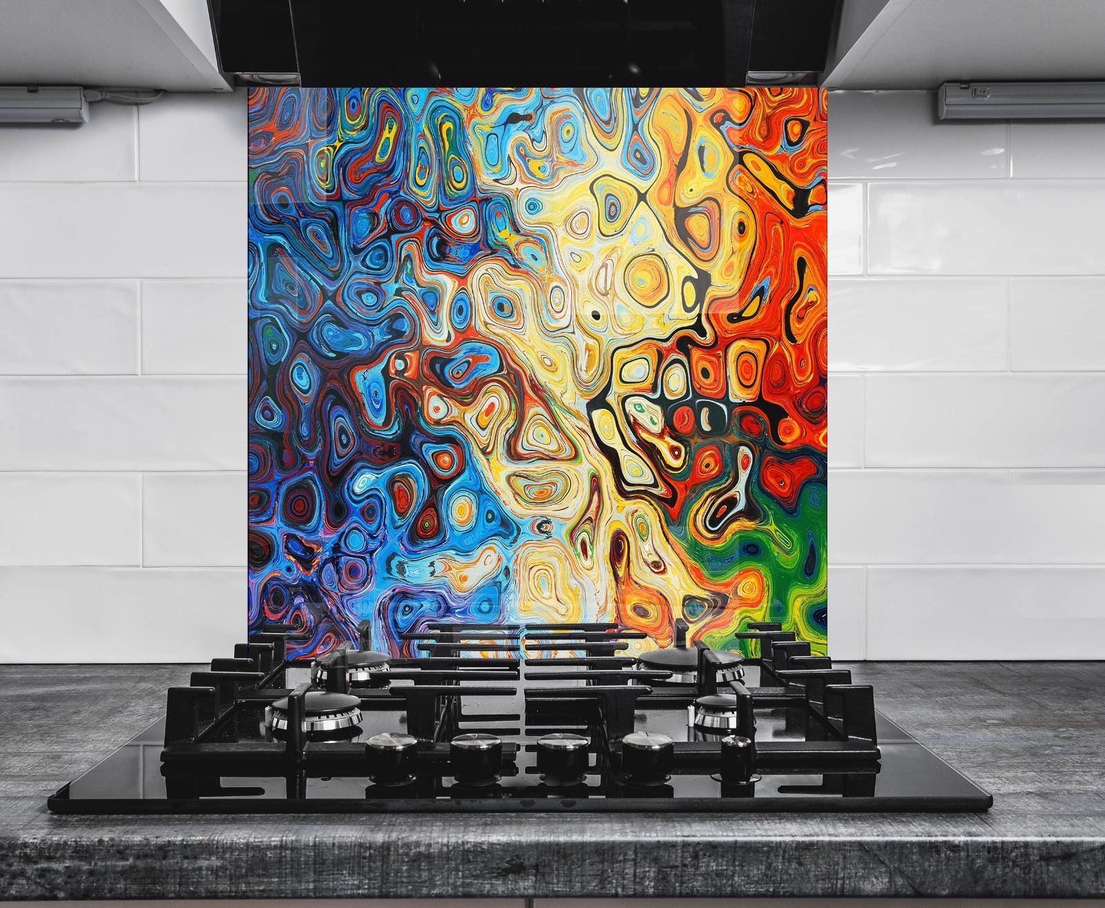 a vibrant, abstract painting with swirling patterns of blue, orange, yellow, and red colors, creating a dynamic and energetic visual effect. The painting is displayed on a wall behind a black stovetop, which is positioned in front of a white countertop. The stovetop has a black griddle on top, adding a modern and sleek touch to the overall design.
