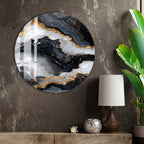a large circular wall art piece with a marble-like texture and gold accents, hanging on a wall next to a lamp and a plant.