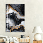 a large abstract painting with a striking black and white marble-like pattern, hanging on a wall above a wooden table with a lamp and a book.