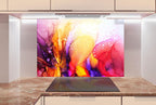 a vibrant abstract painting with a mix of pink, orange, yellow, and purple colors, creating a lively and dynamic visual effect. The painting is displayed on a wall above a kitchen counter, which has a sleek and modern design with white cabinets and a marble countertop.